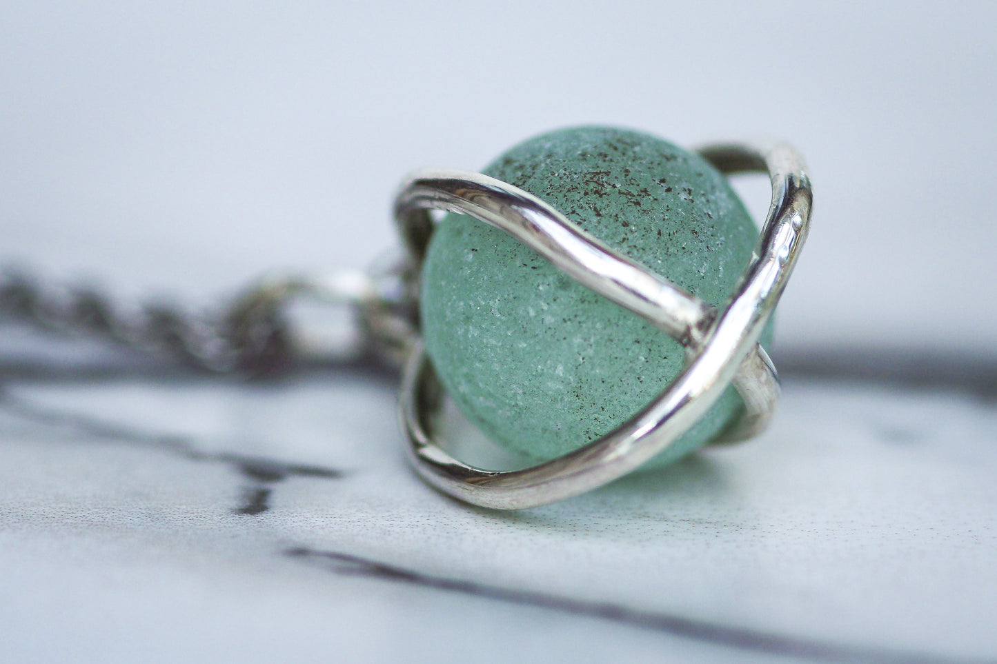 Sterling silver cage pendant holding aqua turquoise sea glass marble, fiddle necklace design