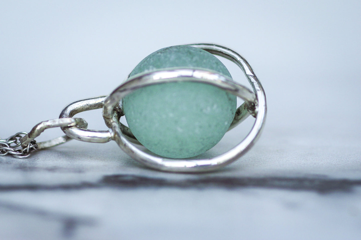 Close-up of rare aqua blue marble pendant in sterling silver, sea glass jewellery UK