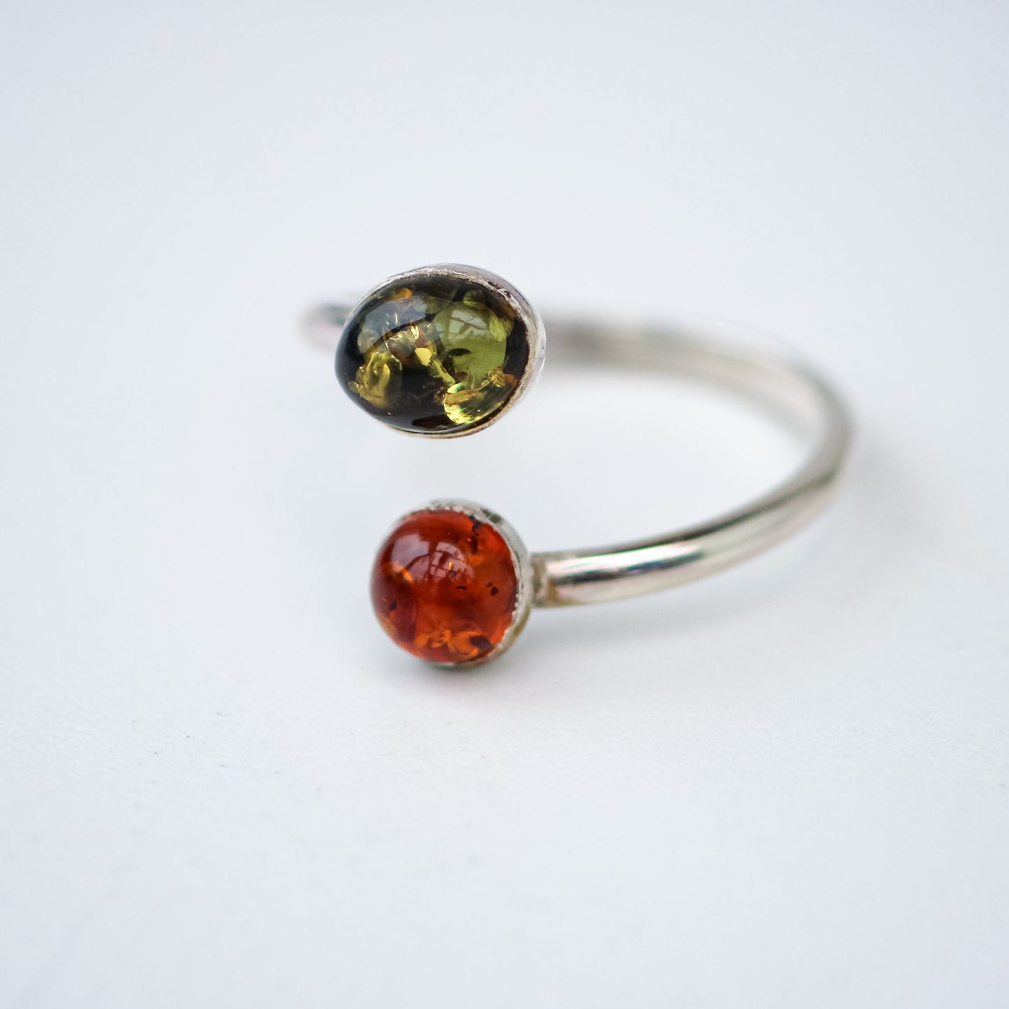 One of a kind handmade amber ring with green and orange Baltic amber. Adjustable sterling silver band. Handcrafted by Louella Jewellery.